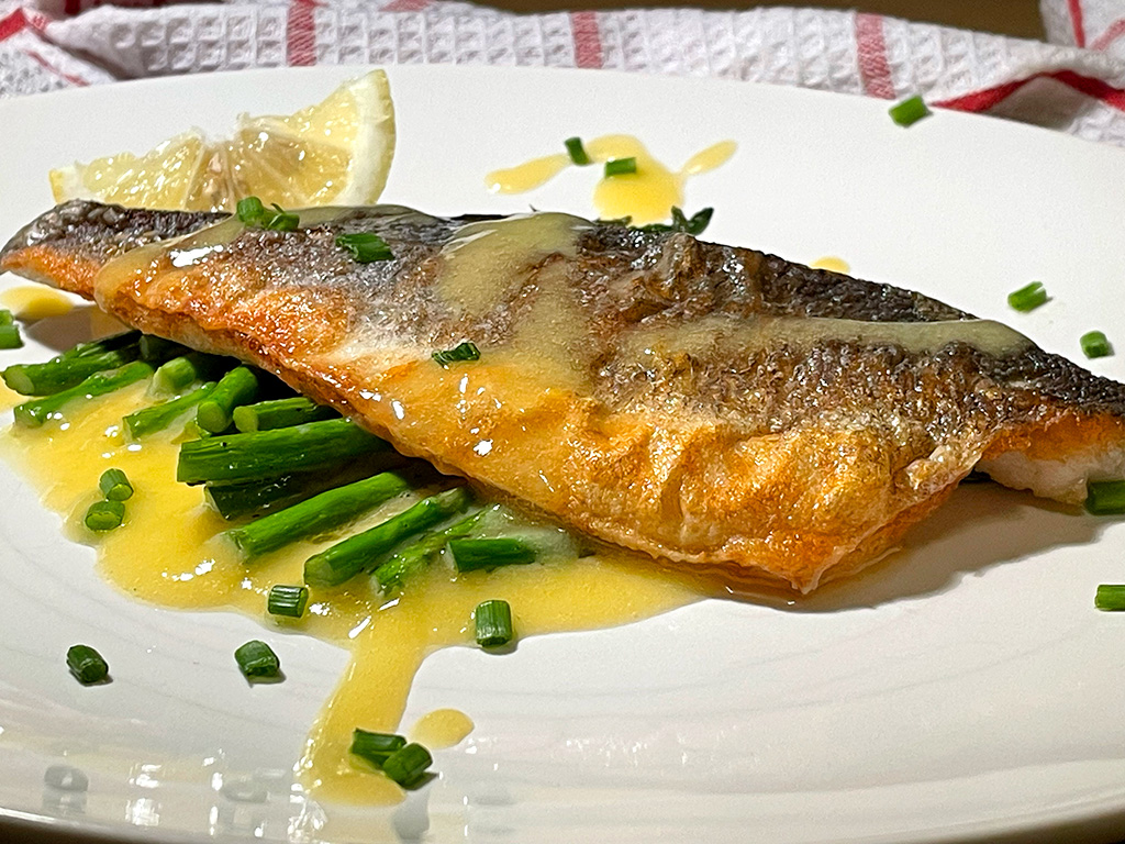 a plate of fish with a butter sauce
