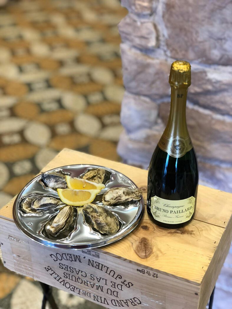 a bottle of champagne next to a plate of oysters