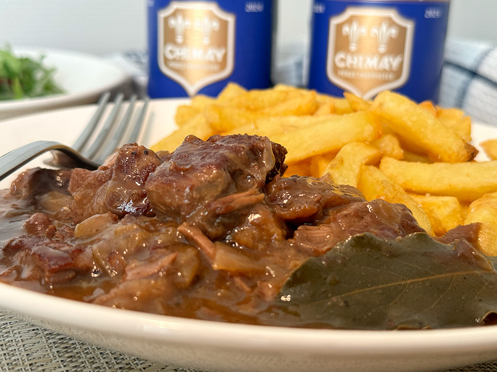 Carbonnade Flamande on a plate with fries and Belgian beer behind