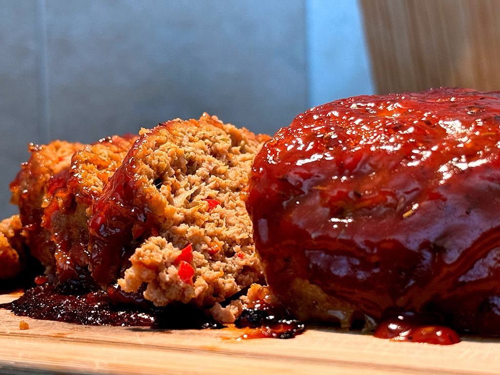 A closeup of homemade meatloaf sliced on a cutting board