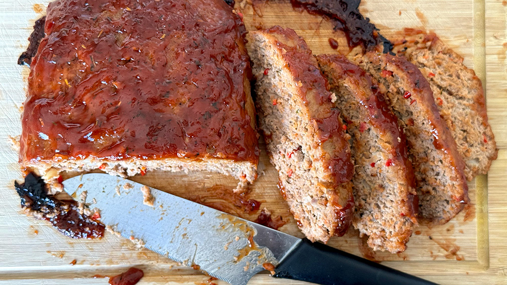 Meatloaf on a cutting board, sliced, with the knife in front